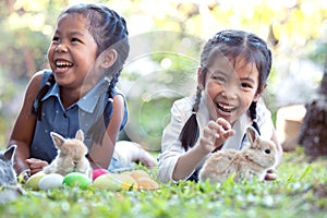 Happy asian child girls playing with little bunny rabbit with love and tenderness in the garden