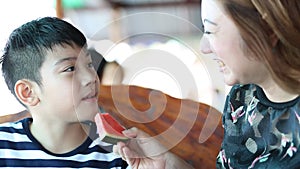 Happy Asian child with mother enjoy eating ripe watermelon .