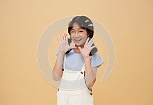 Happy Asian child open mouths raising hands screaming announcement isolated on color background
