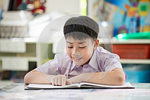 Happy asian child reading book with smile face.