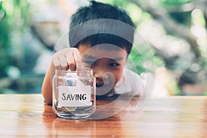 Happy asian children saving money putting coin in glass for wealth and growth of earning in future.