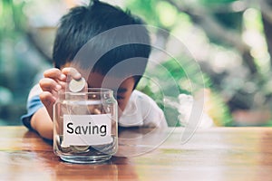 Happy asian children saving money putting coin in glass for wealth and growth of earning in future.