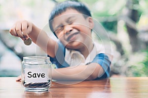 Happy asian children saving money putting coin in glass for wealth and growth of earning in future.