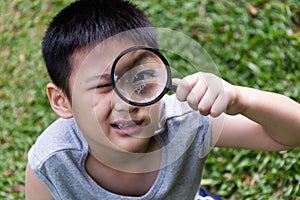 Happy Asian Chinese little boy looking through magnifying glass