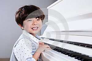 Happy Asian Chinese little boy playing piano at home