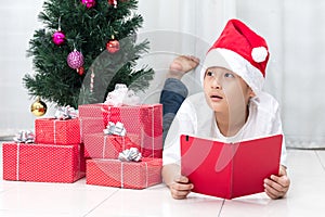 Happy Asian Chinese little boy reading book beside Christmas presents