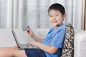 Happy Asian Chinese little boy using laptop with credit card
