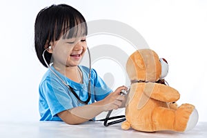 Happy Asian Chinese little doctor girl examine teddy bear