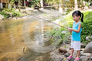 Happy Asian Chinese little girl angling with fishing rod