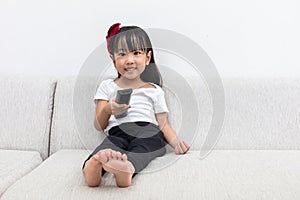 Happy Asian Chinese little girl holding a TV remote control