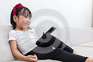 Happy Asian Chinese little girl holding a TV remote control