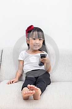 Happy Asian Chinese little girl holding a TV remote control