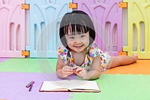 Happy Asian Chinese little girl laying on the floor coloring