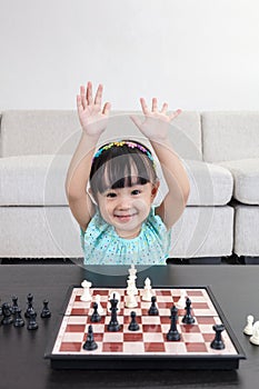 Happy Asian Chinese little girl playing chess chess at home