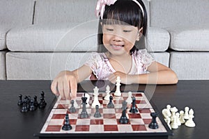 Happy Asian Chinese little girl playing chess chess at home