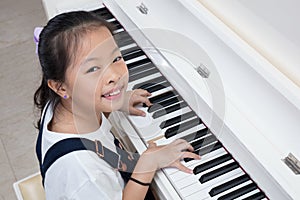 Happy Asian Chinese little girl playing classical piano at home