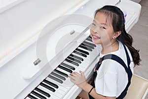 Happy Asian Chinese little girl playing classical piano at home