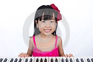 Happy Asian Chinese little girl playing electric piano keyboard