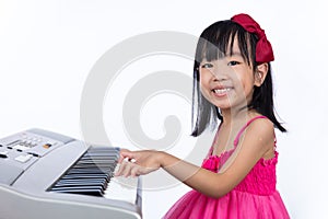 Happy Asian Chinese little girl playing electric piano keyboard