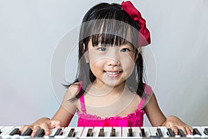 Happy Asian Chinese little girl playing electric piano keyboard