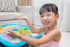 Happy Asian Chinese little girl playing kinetic sand at home