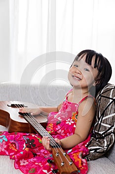 Happy Asian Chinese little girl playing ukele