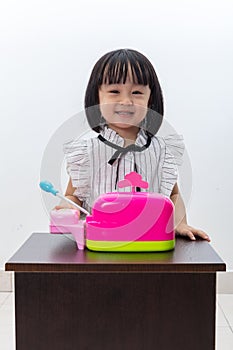 Happy Asian Chinese little girl pretending as cashier with toys