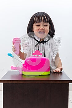 Happy Asian Chinese little girl pretending as cashier with toys