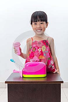 Happy Asian Chinese little girl pretending as cashier with toys