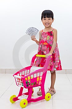 Happy Asian Chinese little girl pushing toy trolley holding cash