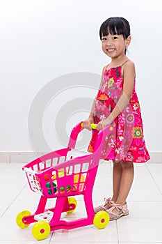 Happy Asian Chinese little girl pushing toy trolley