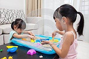 Happy Asian Chinese little girls playing kinetic sand at home