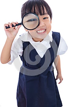 Happy Asian Chinese little primary school girl holding magnifying glass