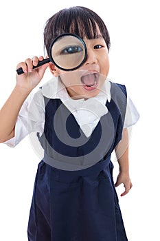 Happy Asian Chinese little primary school girl holding magnifying glass