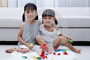Happy Asian Chinese little sisters playing blocks on the floor