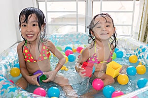 Happy Asian Chinese little sisters playing in the inflatable poo