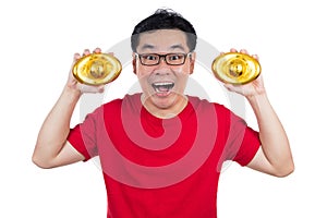 Happy Asian Chinese man wearing red shirt holding ingot