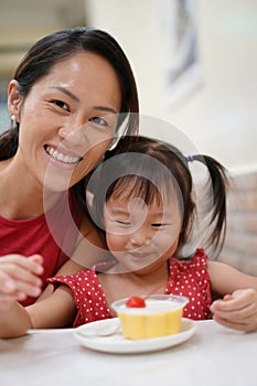 Happy Asian chinese mother and daughter enjoying a bowl of dessert