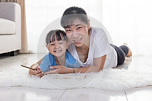 Happy Asian Chinese mother and daughter writing on the floor
