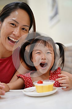 Happy Asian chinese mother and surprised daughter enjoying a bowl of dessert