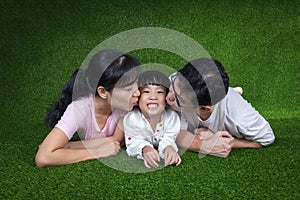 Happy Asian Chinese parents and daughters lying on the grass