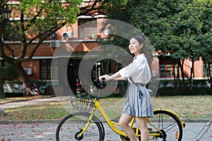 Happy Asian Chinese pretty girl riding a bike wear student suit in school