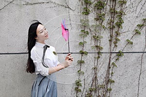 Happy Asian Chinese pretty girl wear student suit in school playing windmill