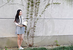 Happy Asian Chinese pretty girl wear student suit in school reading book