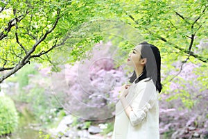 Happy Asian Chinese pretty woman stand under tree in nature in spring outdoor