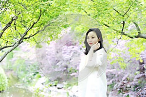 Happy Asian Chinese pretty woman stand under tree in nature in spring outdoor