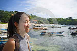 Happy Asian Chinese woman with backpack in beach trip tourist excursion smiling sweet in Summer holiday and vacation travel