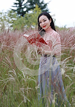 Happy Asian Chinese woman girl feel freedom sweet dream pray flower field autumn fall park grass lawn hope nature read book school