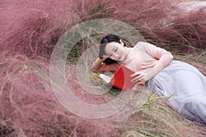 Happy Asian Chinese woman girl lying on grass dream pray flower field autumn fall park lawn hope nature read book knowledge