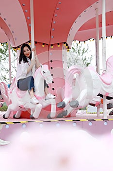 Happy Asian Chinese woman girl on Merry-go-round in a Amusement Park